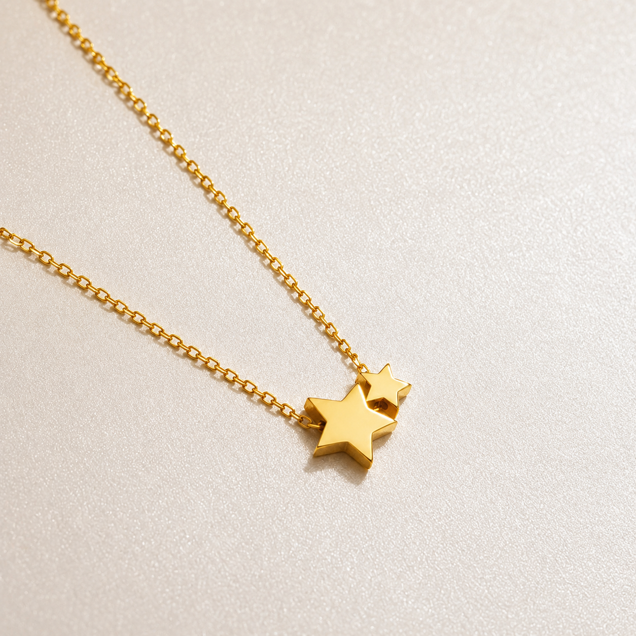 Gold necklace with star pendants on a light beige background